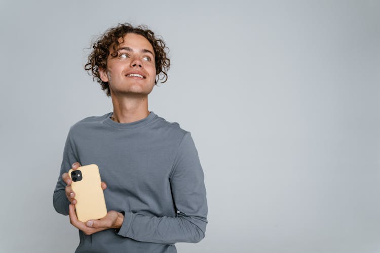 Man In Gray Crew Neck Long Sleeve Shirt Holding Iphone