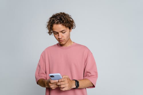 Free Man in Pink Crew Neck T-shirt Holding Blue Smartphone Stock Photo