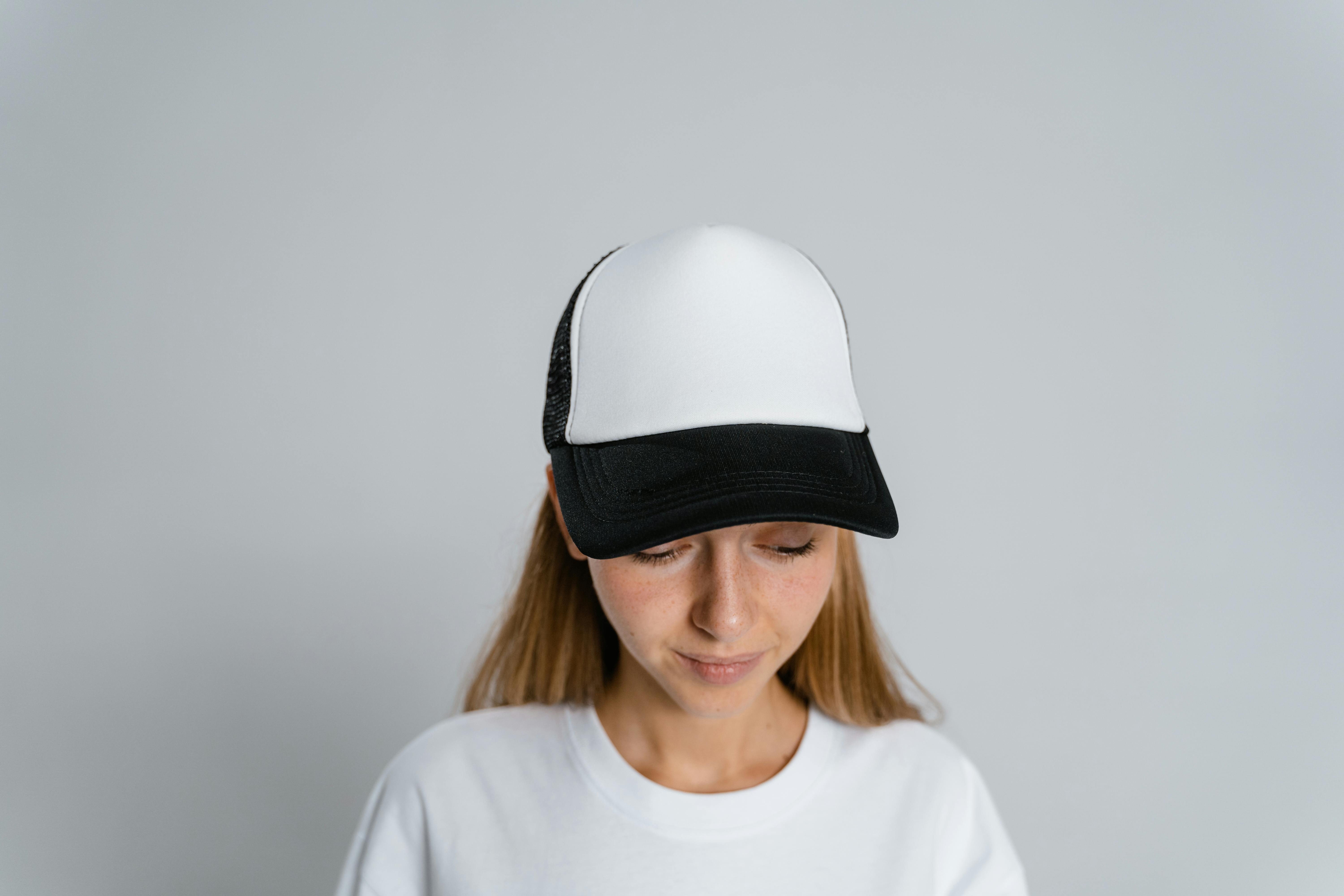 Woman in a white and black cap looking down in a studio setting.