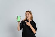 Woman in Black Crew Neck T-shirt Holding Green and White Iphone Case