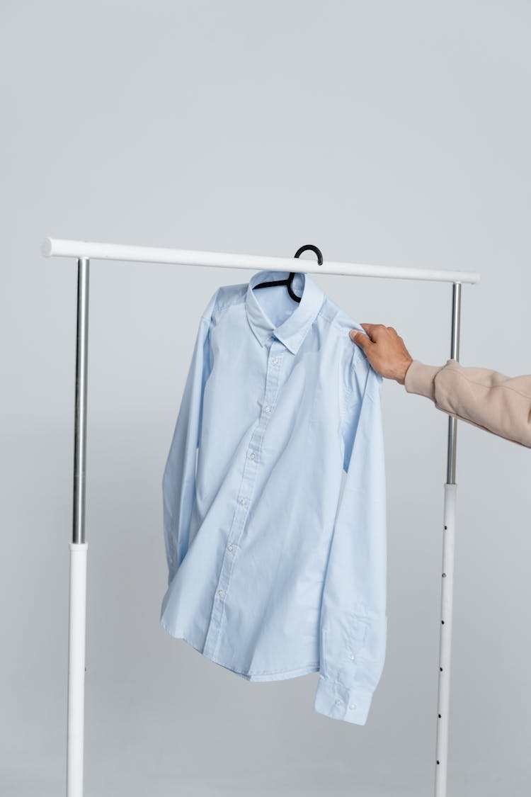 Blue Button Up Shirt Hanging On White Metal Bar