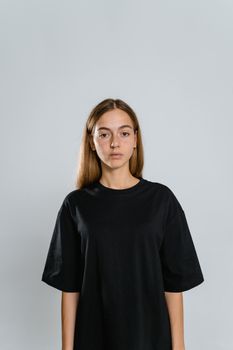 Studio shot of a woman wearing a black t-shirt, standing against a plain background, ideal for mockup designs.