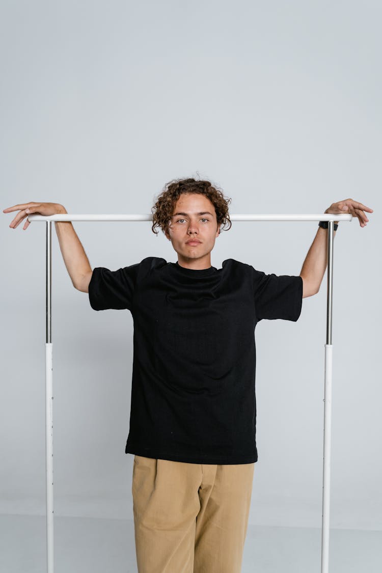 A Man In Black Shirt Hanging His Hands On A Steel Bar