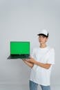 Woman in White Crew Neck T-shirt Holding Green Laptop Computer