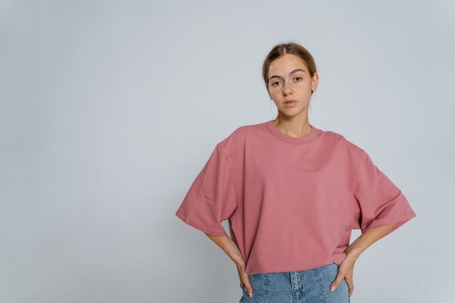 Editorial portrait of a model in a soft oversized tee, clean white studio background.