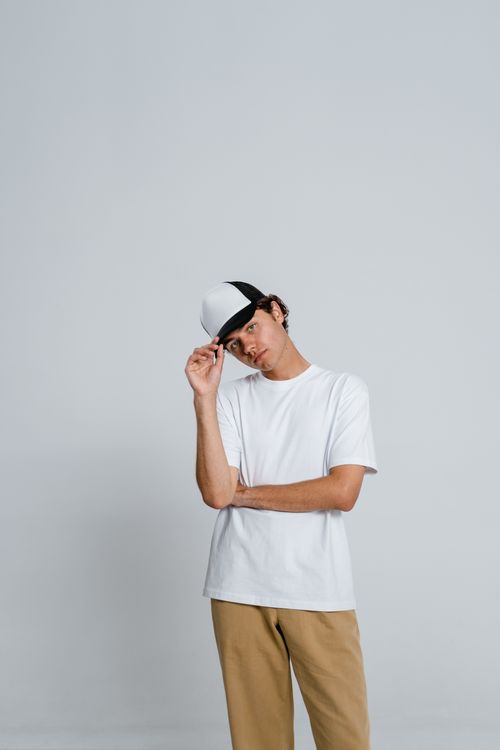Person in a blank white t-shirt and cap on a neutral background — photo by MART PRODUCTION on Pexels