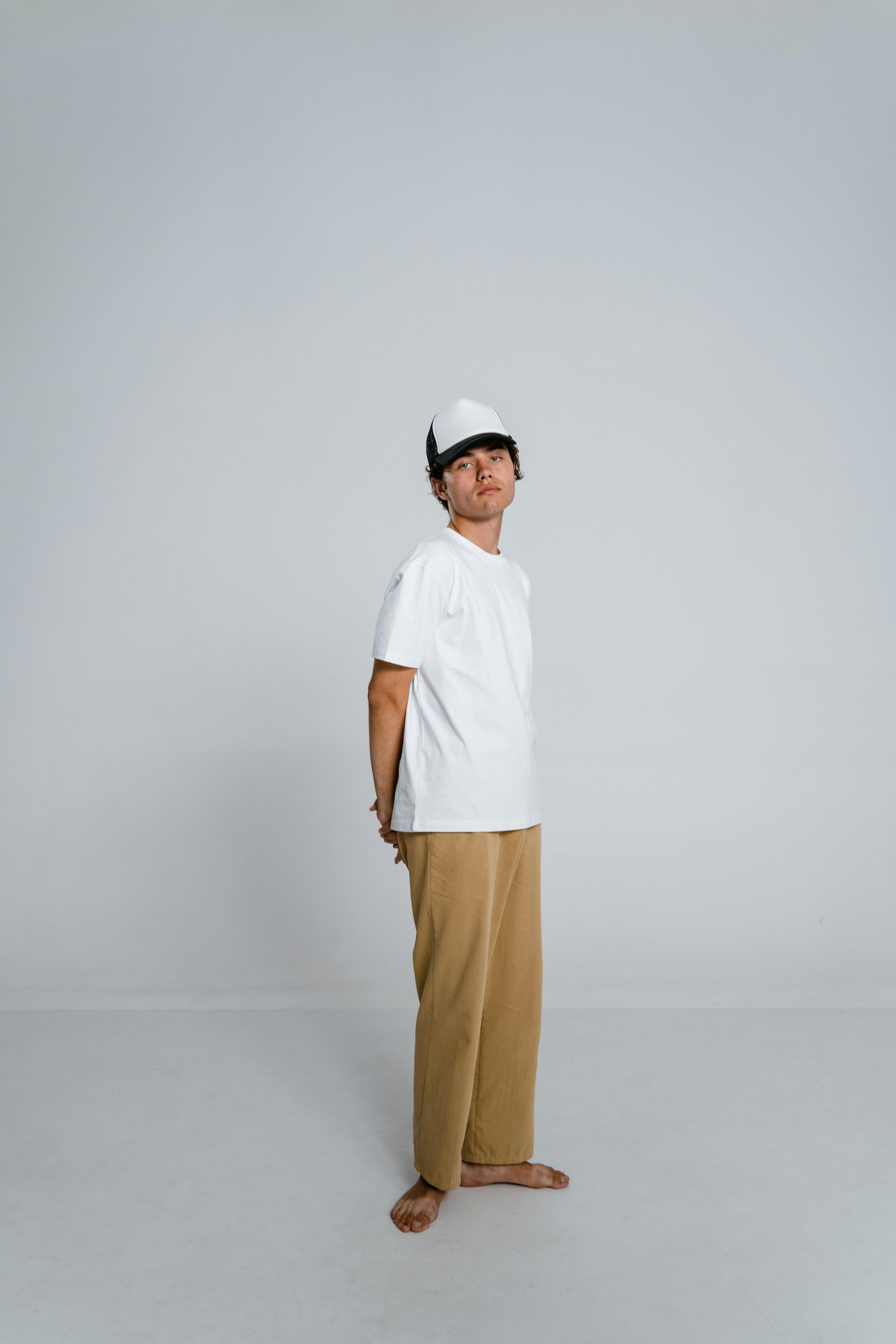 Man in white crew neck tshirt and brown pants sitting on white chair photo   Free Male pose Image on Unsplash