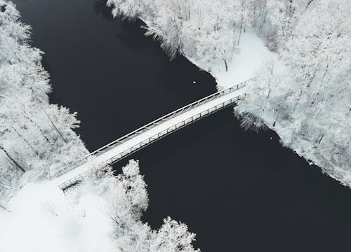 An Aerial View of a Snow Covered Bridge Over a Lake During Winter
