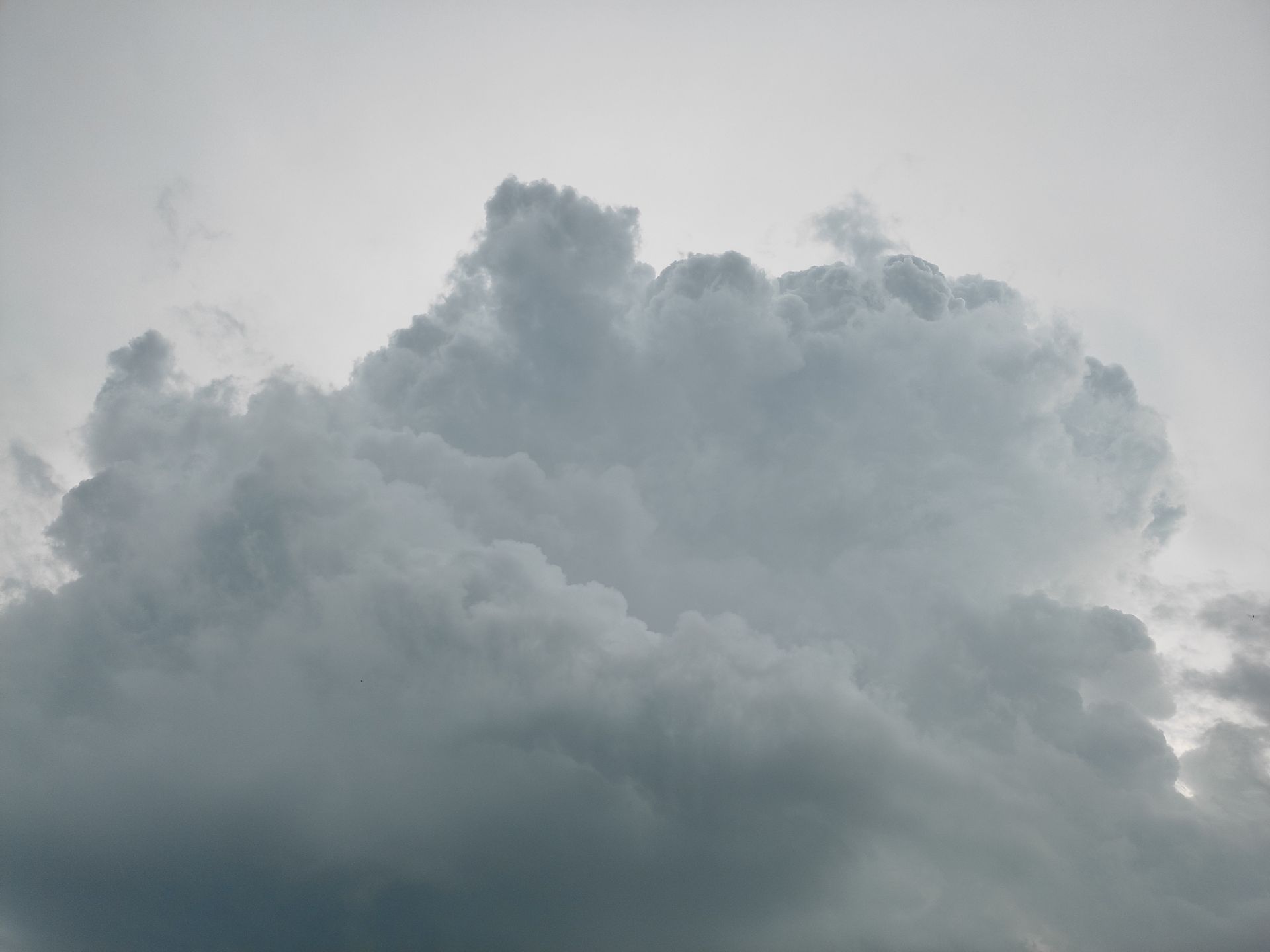 A massive cumulus cloud formation in a moody, overcast sky, showcasing weather dynamics.
