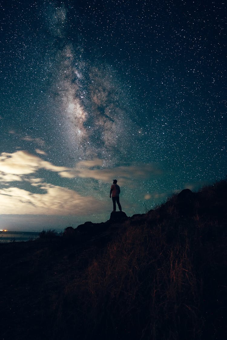 Silhouette Of Person Standing On Rock Under Blue Sky During Night Time