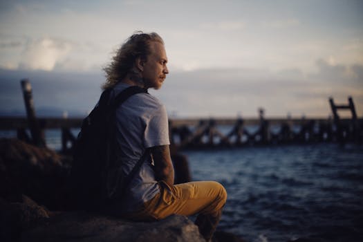 A man relaxes by the ocean at sunset, enjoying the serene view.