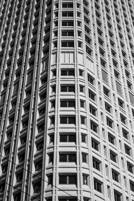 Monochrome view of a tall, modern high-rise building showing intricate window patterns.