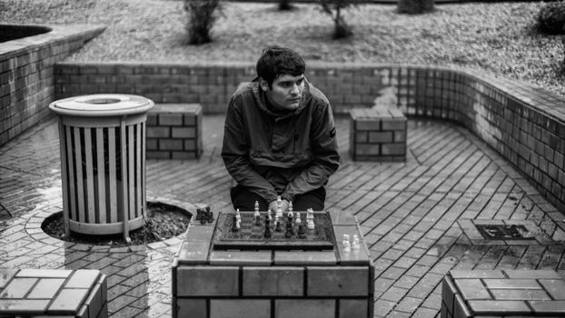 A Man in Black Jacket Playing Chess