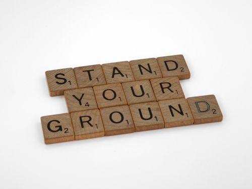 Free Scrabble tiles spelling "Stand Your Ground" on a white background. Stock Photo