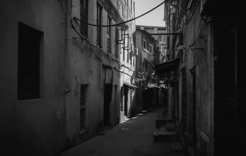Grayscale Photography of Alley Between Concrete Buildings