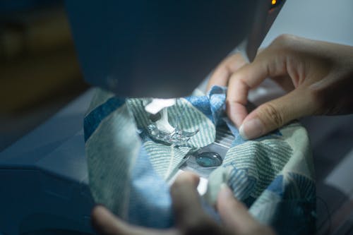 A Person Sewing a Fabric with a Sewing Machine