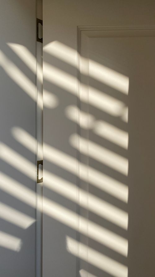 Free Dramatic shadows cast on a white door by sunlight through blinds, creating a captivating pattern. Stock Photo