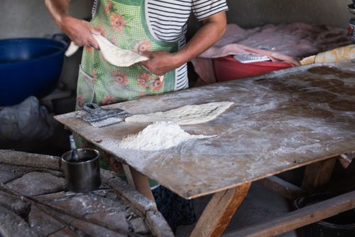 Free A baker kneads dough on a wooden table in a rustic kitchen, showcasing traditional bread-making. Stock Photo