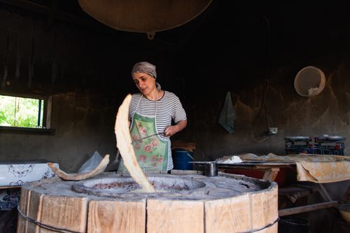 Free Woman preparing traditional bread in a rustic tandoori oven setting. Stock Photo