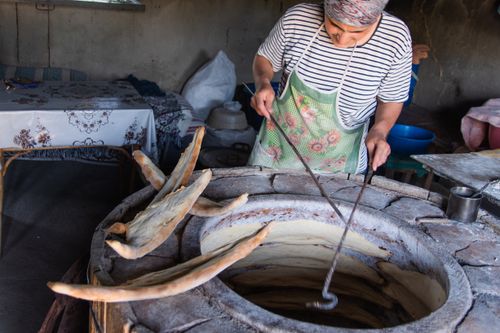 Free Woman baking naan bread in a traditional tandoor oven, showcasing ancient culinary techniques. Stock Photo