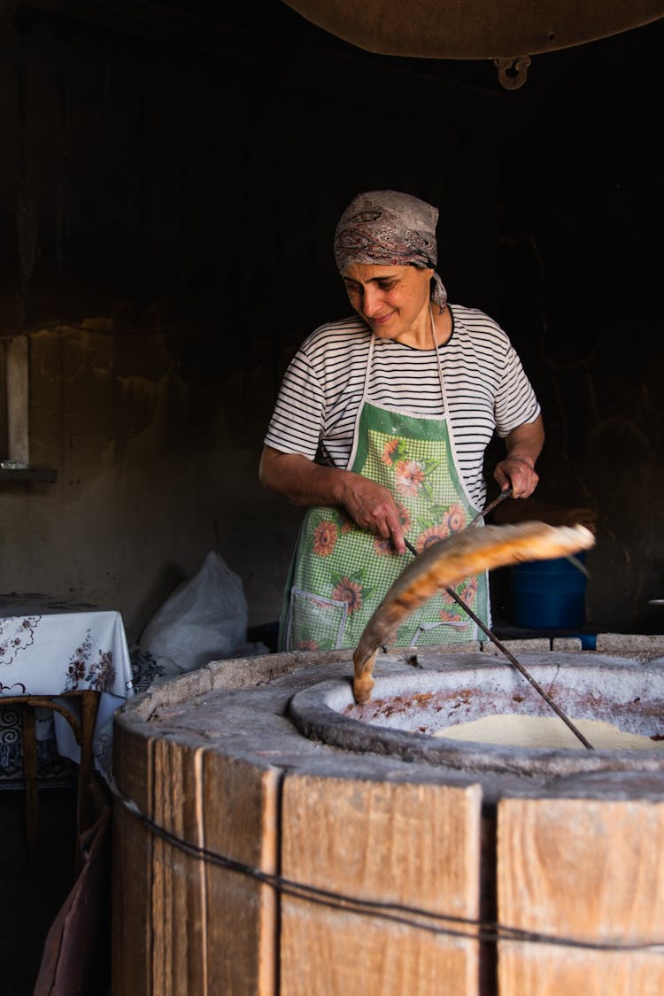 A Woman Cooking On The Tandoori Oven