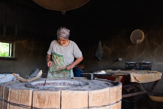 A woman preparing food in a traditional tandoori oven, showcasing culinary skills indoors.