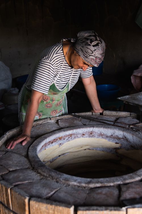 Free A chef prepares traditional bread in a tonis oven, capturing cultural culinary artistry. Stock Photo