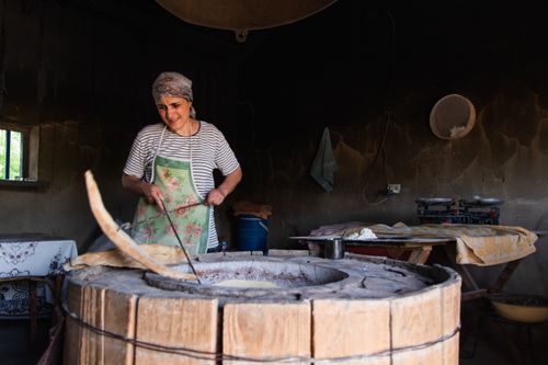 Free A woman preparing traditional Georgian bread in an old-fashioned, rustic bakery setting. Stock Photo