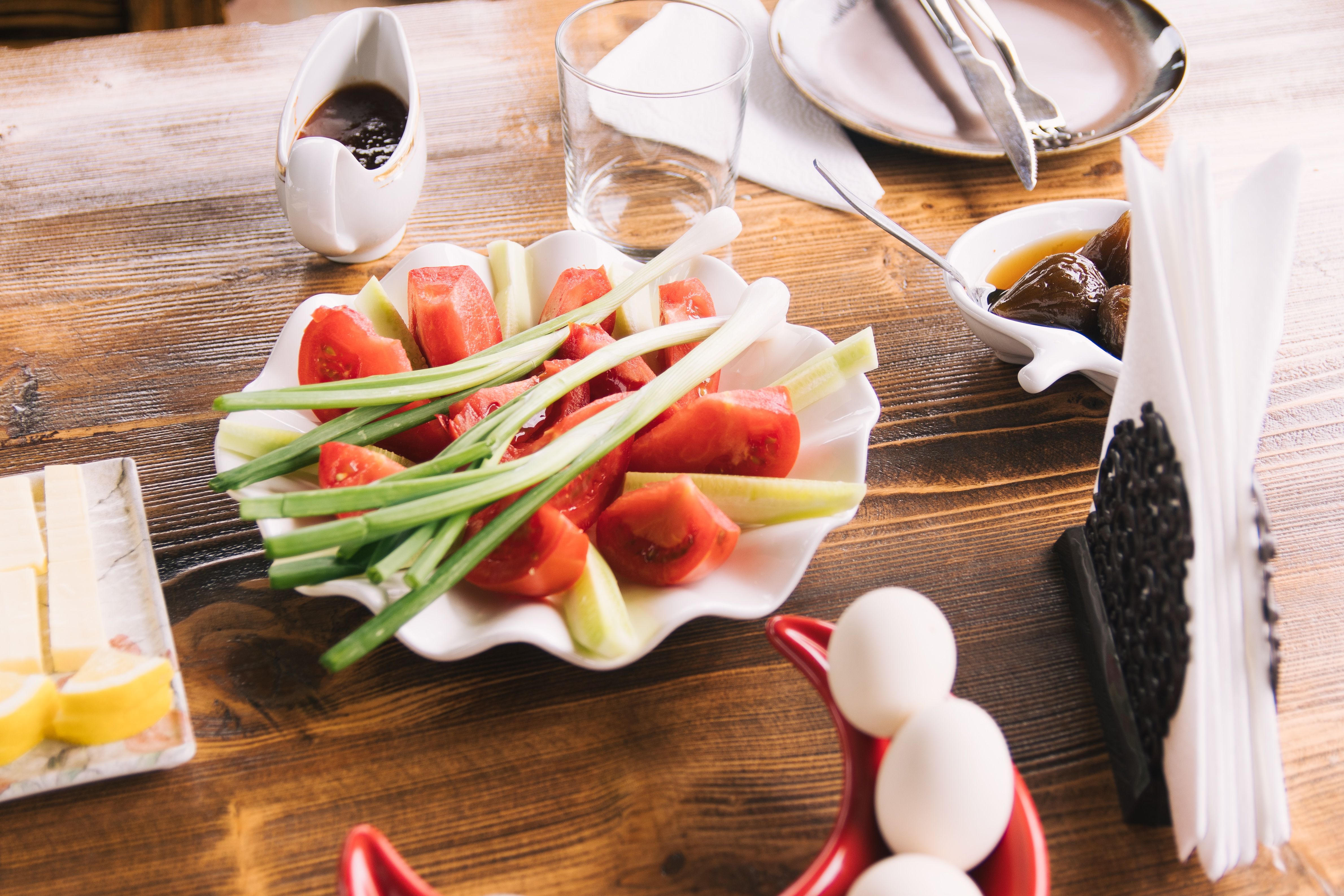 Close-up of a fresh vegetable salad with tomatoes and chives on a wooden table.