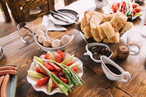 Free A delicious rustic breakfast featuring fresh bread, eggs, vegetables, and sauces on a wooden table. Stock Photo