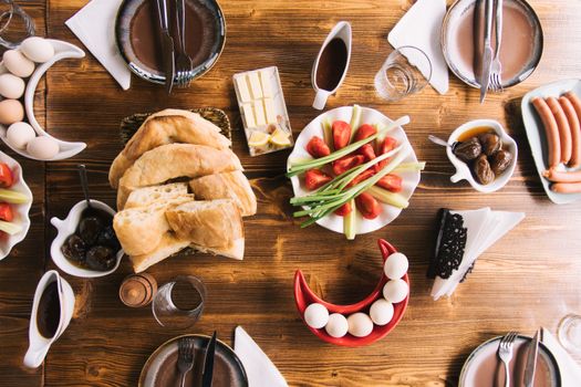 A delightful breakfast spread with bread, vegetables, meats, and sauces on a wooden table.