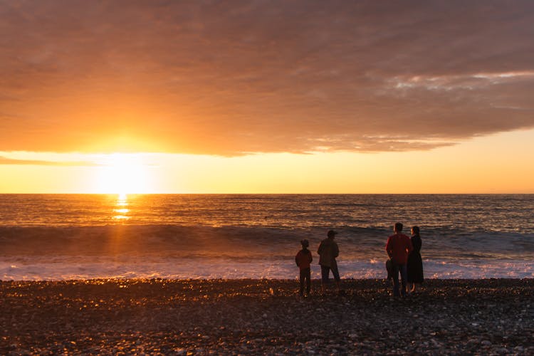 Photo Of A Family On A Beach During Sunset