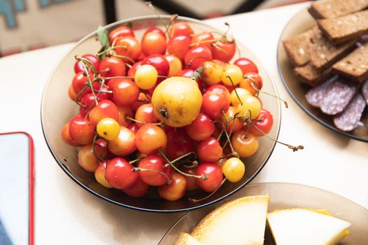 A bowl of fresh cherries and sliced melon on a table, perfect for healthy eating.