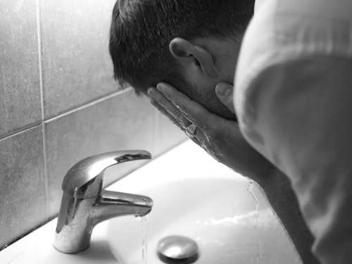 Free Grayscale Photo of Person Washing His Face on the Sink Stock Photo
