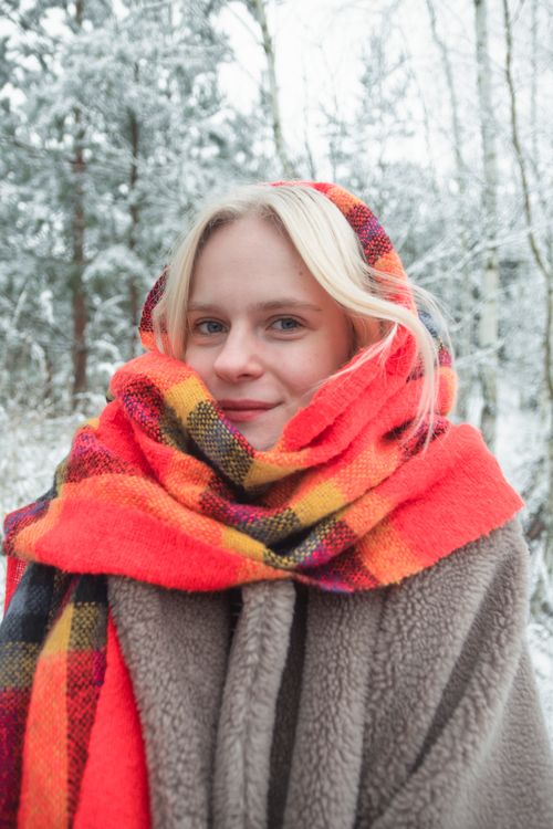 Free Blonde woman wrapped in a vibrant scarf in a snowy forest setting. Stock Photo