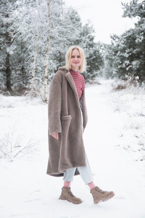 A Woman in Brown Fur Coat Standing on a Snow Covered Ground