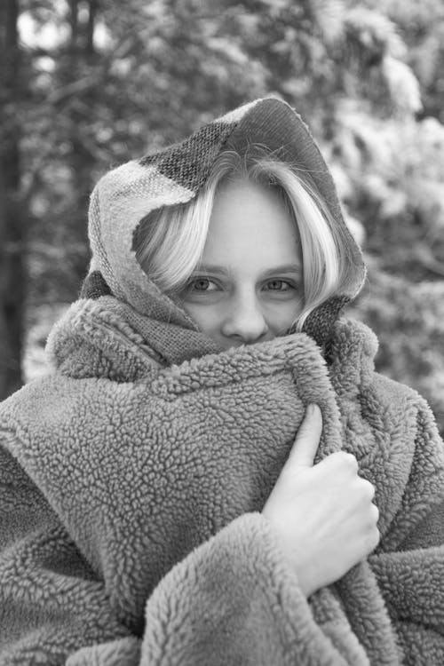 Grayscale Photo of a Woman Wrapping Herself with a Fur Coat