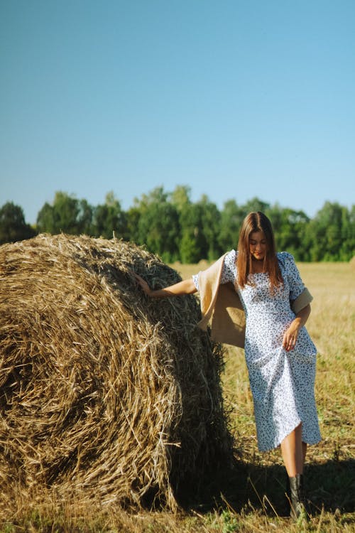 Woman in Floral Dress Standing Near the Hay Bale