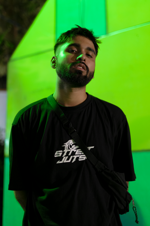 Free Stylish portrait of a young man in street wear against a vibrant green background. Stock Photo