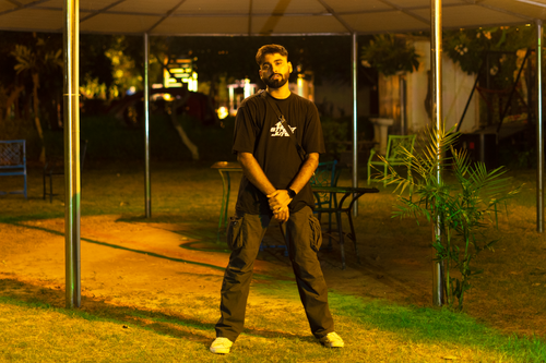 Free A young man in casual attire posing confidently outdoors at night. Stock Photo