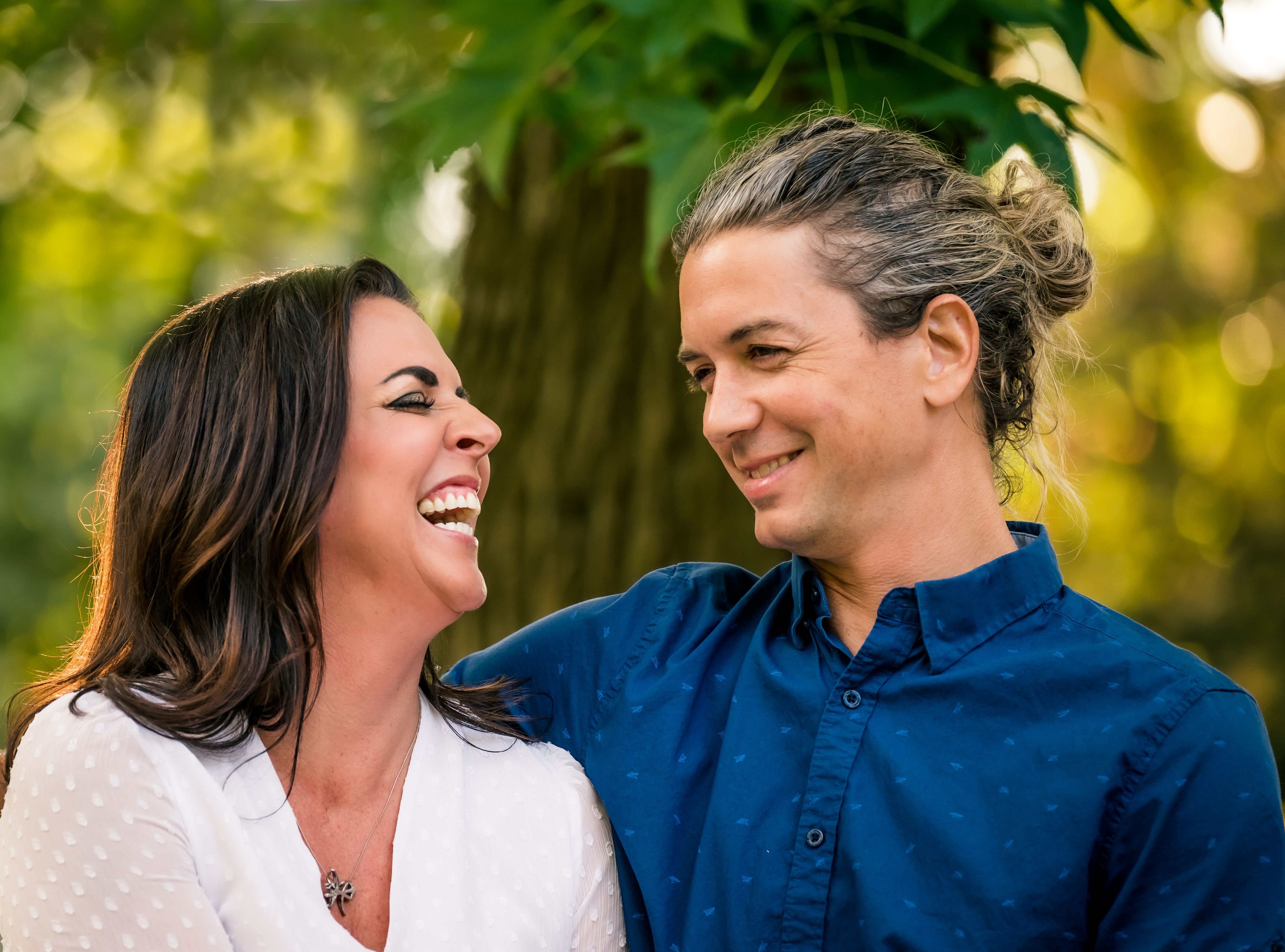 A happy couple laughing together outdoors, capturing a joyful moment in nature.