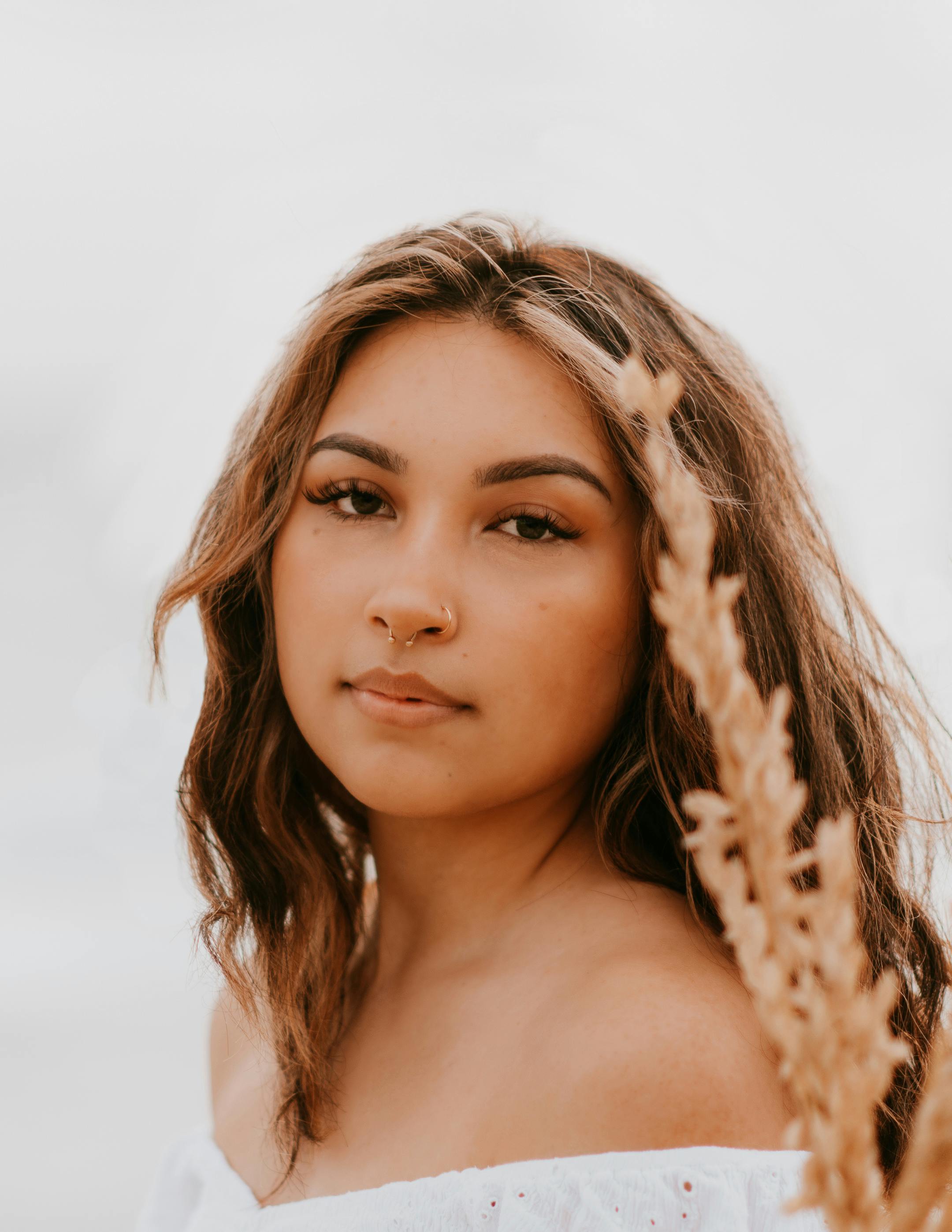 Close-up portrait of a young woman with a serene expression and natural beauty in soft lighting.