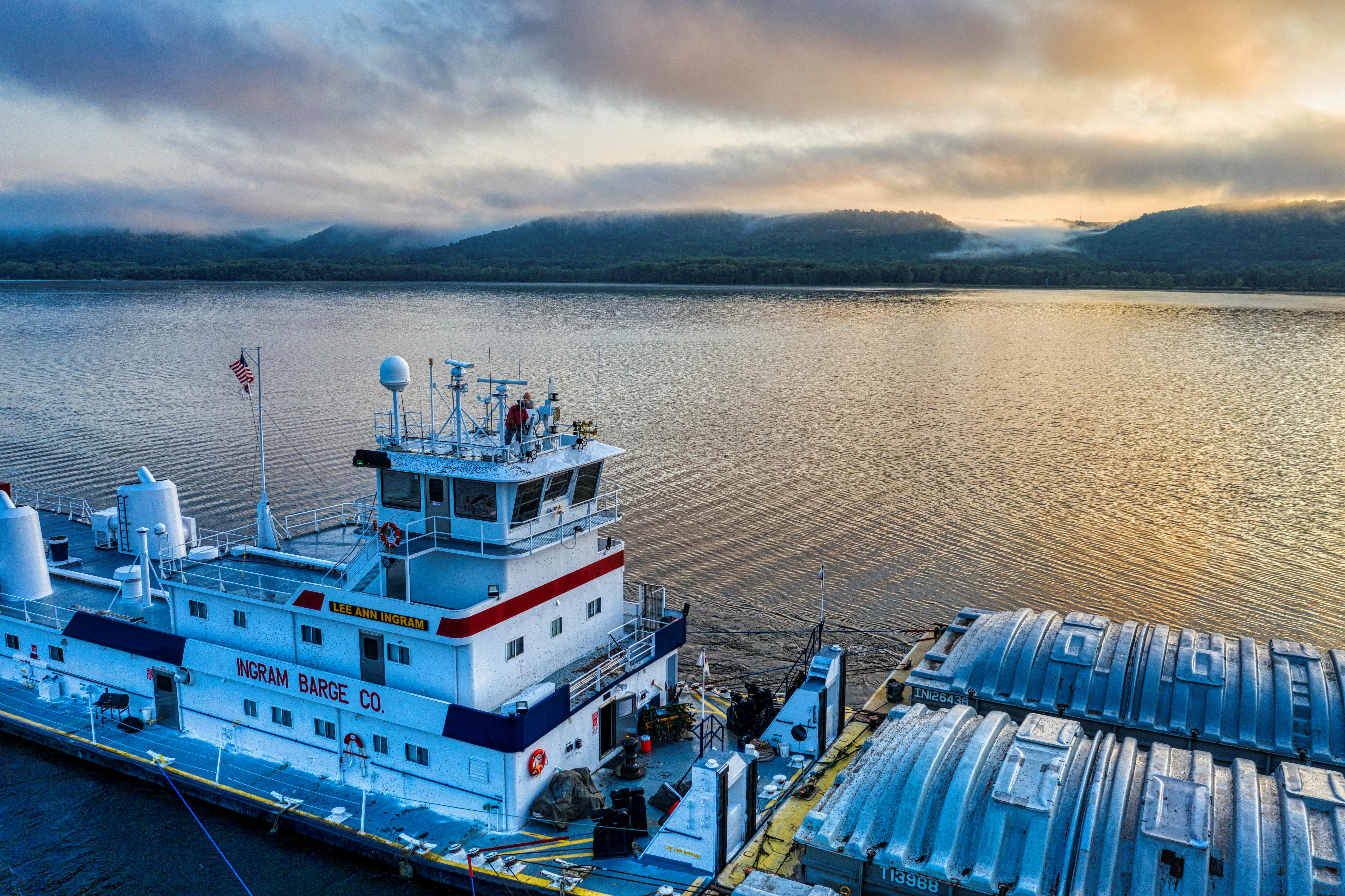 Free Stunning view of a barge on the Mississippi River with morning light and misty hills in the background. Stock Photo