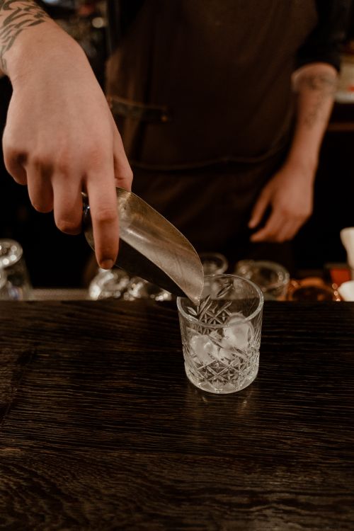 Free Close-up of a bartender scooping ice into a crystal glass at a bar. Stock Photo
