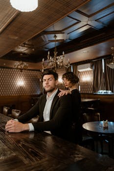 A man and woman in a sophisticated, vintage bar setting, exuding elegance and mystery.