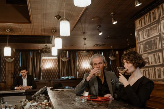 A sophisticated group enjoying drinks at a retro-style bar with elegant decor.