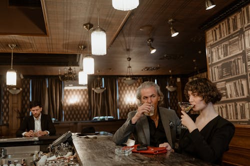 A sophisticated group enjoying drinks at a retro-style bar with elegant decor.