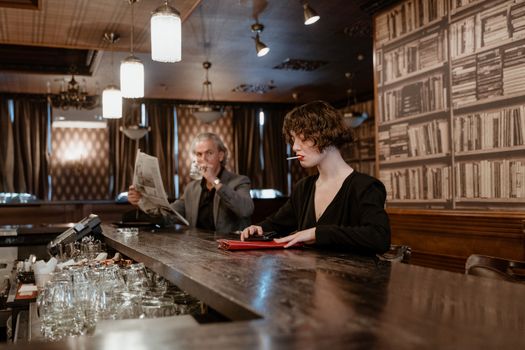 Vintage-style bar scene with woman in black dress smoking and man reading newspaper.