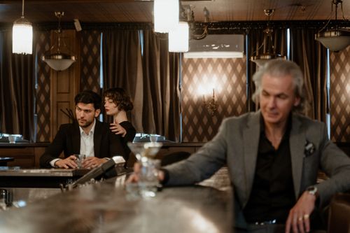 Free Three adults in a sophisticated bar setting, enjoying drinks and conversation. Stock Photo
