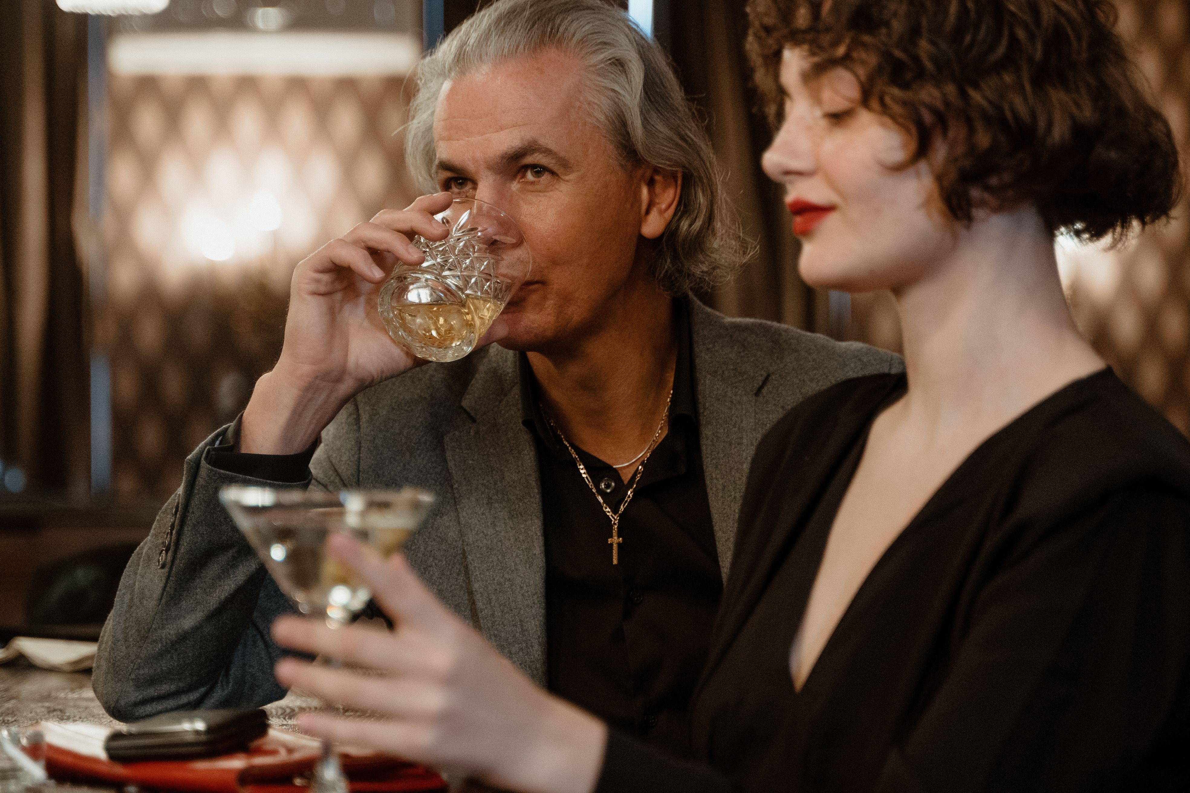 Sophisticated couple sipping classy cocktails in an upscale bar setting, exuding elegance and style.